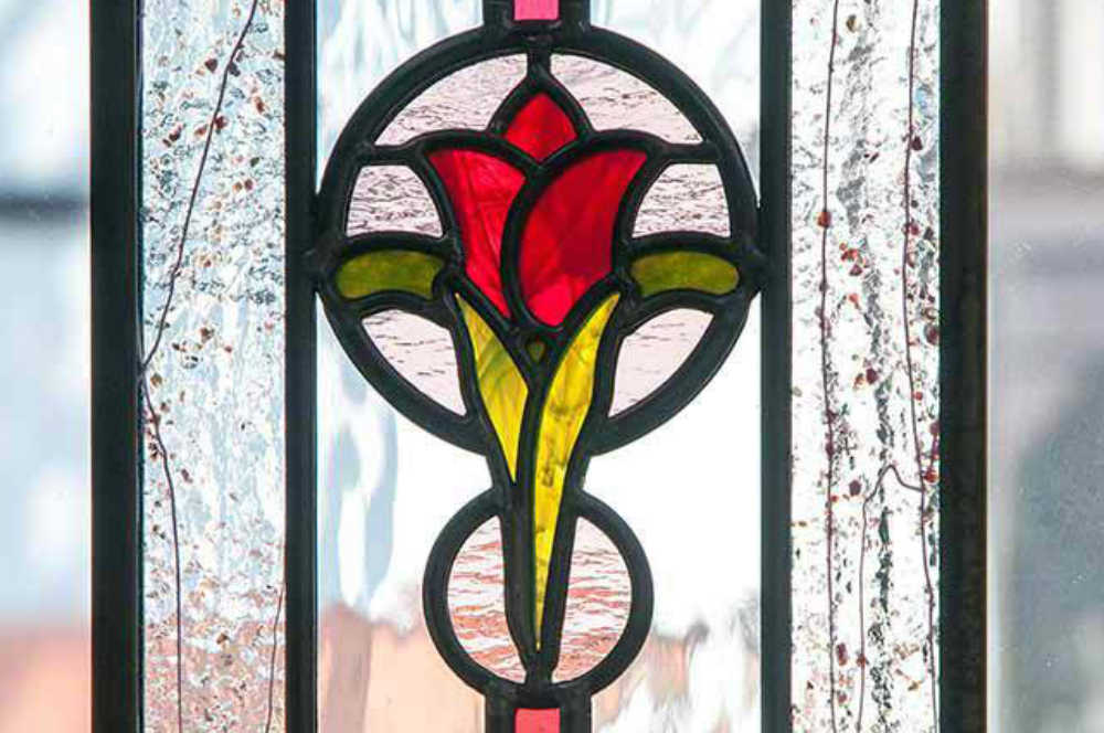 赤いお花のオーナメント部分の拡大写真。両脇のフリットガラスが効果的なステンドグラス。