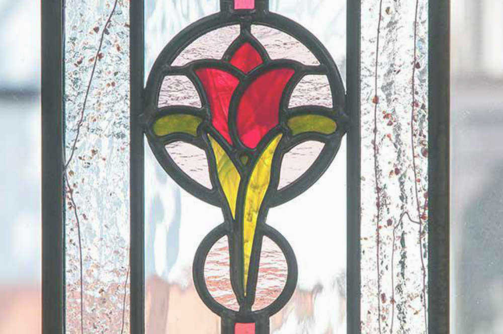 赤いお花のオーナメント部分の拡大写真。両脇のフリットガラスが効果的なステンドグラス。