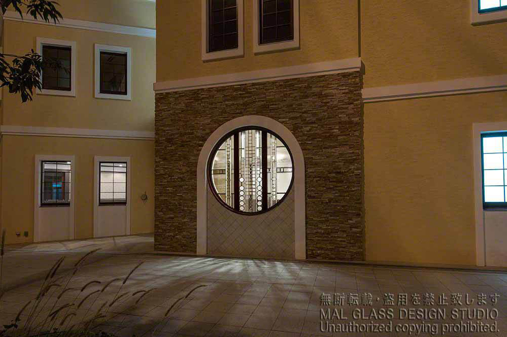 夕刻外から見た丸窓のステンドグラス。