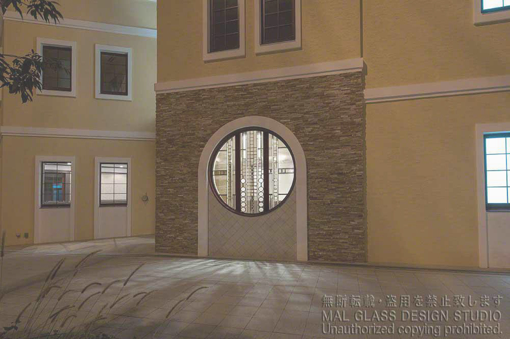 夕刻外から見た丸窓のステンドグラス。